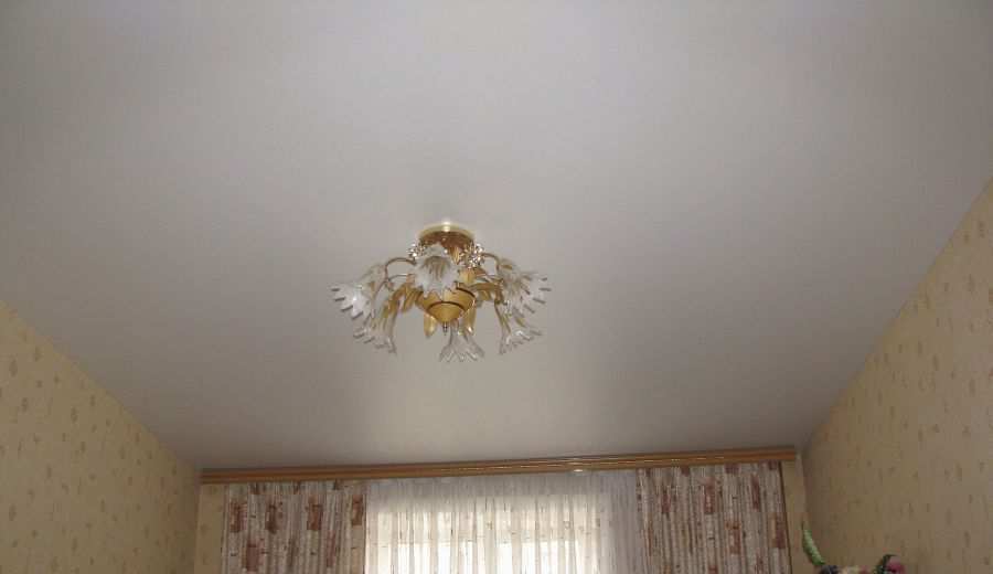 Сатиновый натяжной потолок белого цвета в спальной комнате