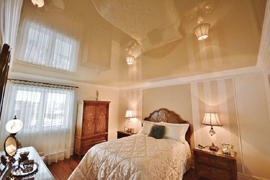 Глянцевый натяжной потолок кремового цвета в спальной комнате