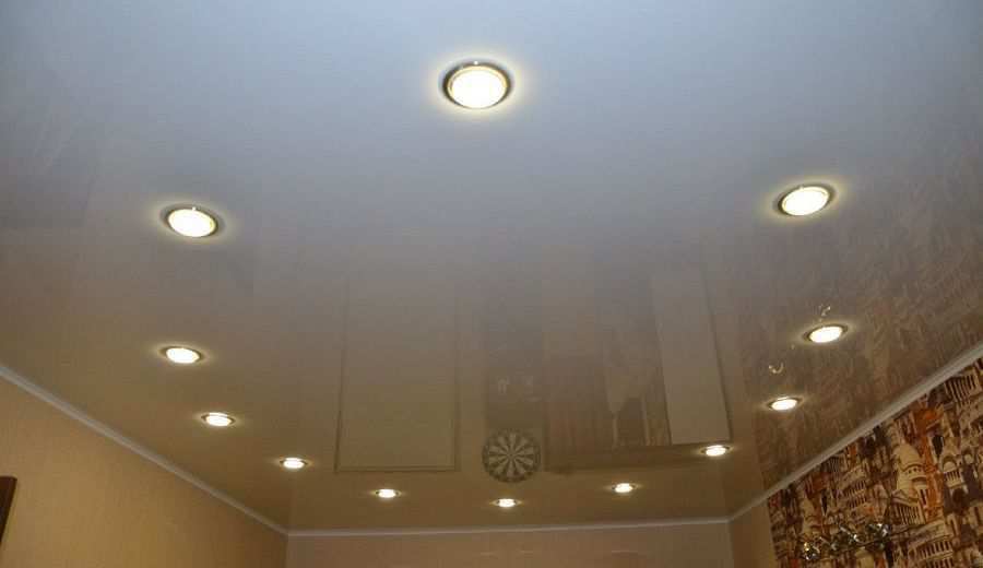 Фотография глянцевого натяжного потолка белого цвета с точечными светильниками в зале